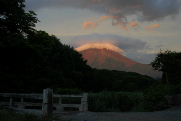 日の出前の暗さの中で朝日を浴びて光る富士山